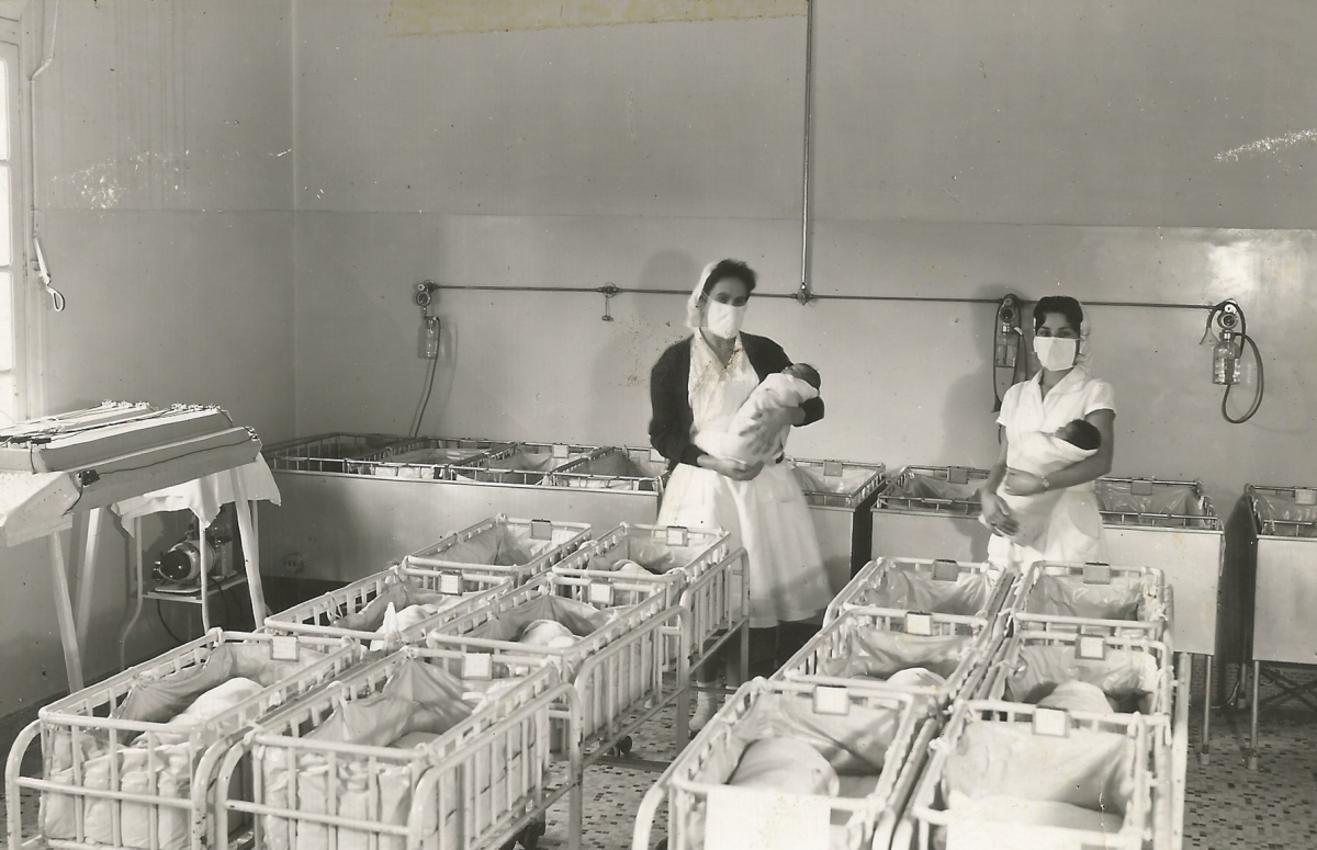 duas enfermeiras posam com bebês recém nascidos no berçario da antiga maternidade alvarenga